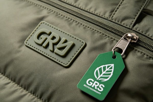 Close-up shot of sustainable GRS certified recycled nylon fabric and custom embossed brand patch on a puffer bag